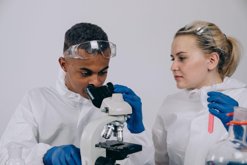 Scientists examining a sample with a microscope as part of how researchers study therapeutic compounds.